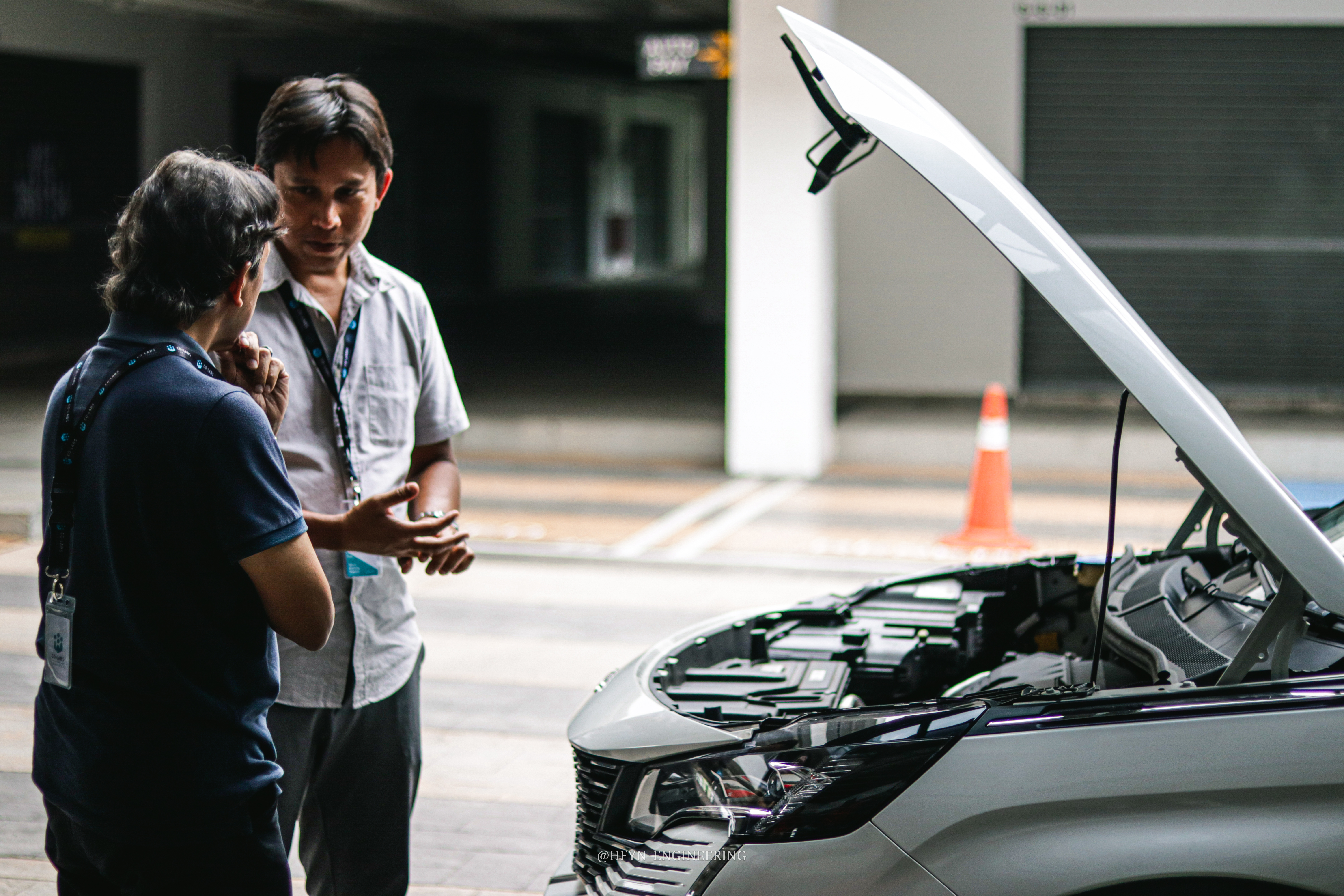 Engineers inspecting the battery compartment of an open electric-vehicle hood
