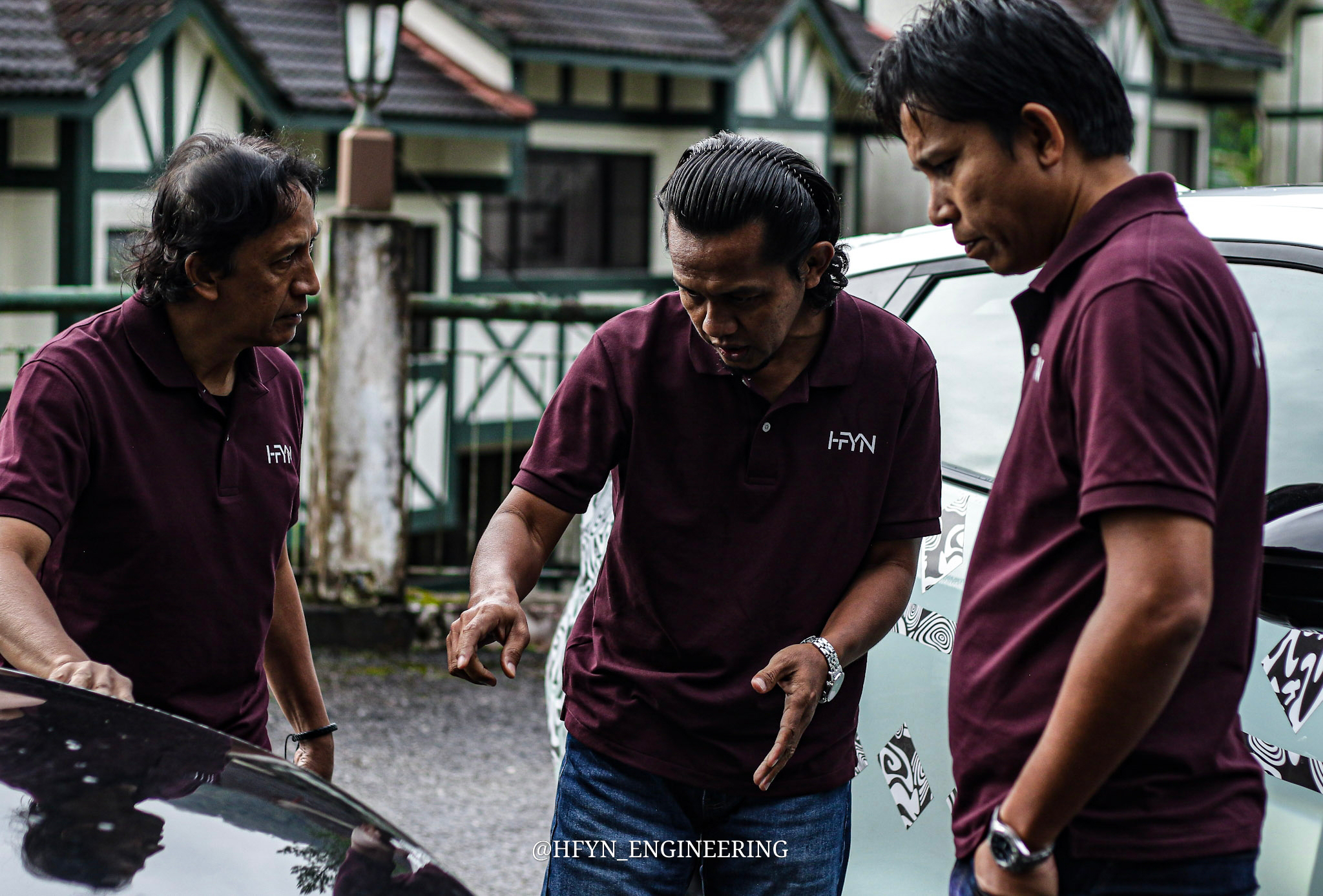 Three engineers inspecting a camouflaged vehicle